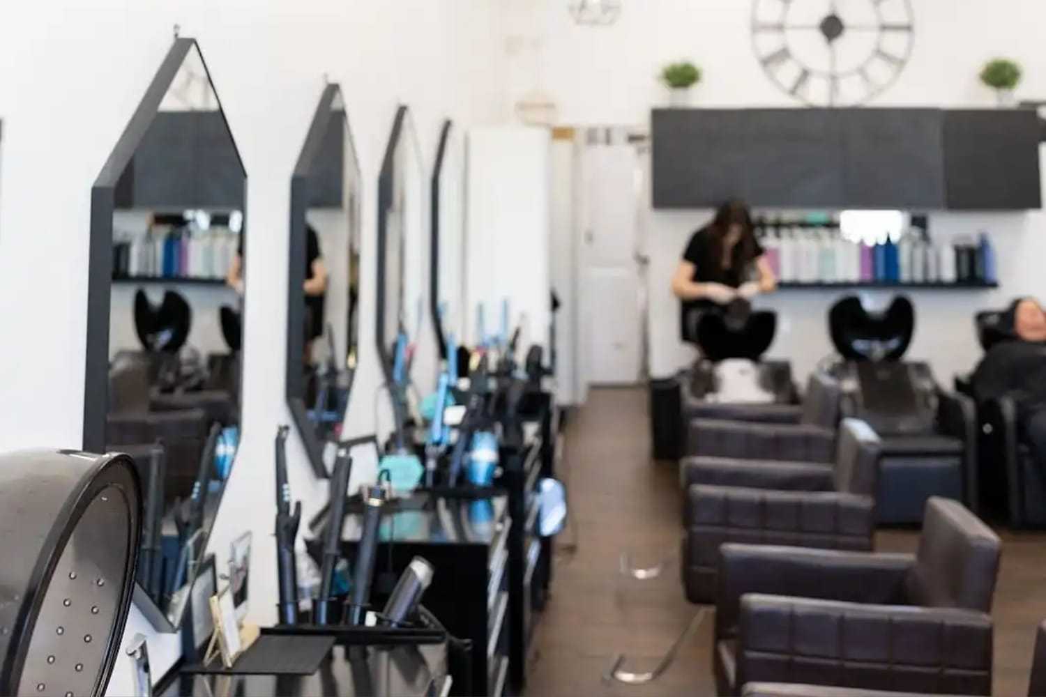 Hair salon interior with mirrors, styling chairs, and washing stations.